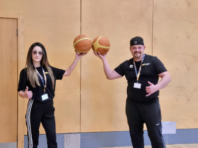 Ana Maria and Sorin Sima standing, each holding a basketball in one hand raised and held in a toasting gesture.