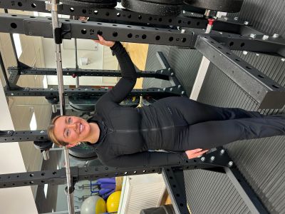 Natalie Dott standing and smiling in front of a weight machine.